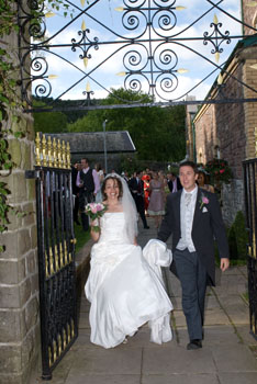Bride and Groom walk through gate from theatre gardens at Craig y Nos Castle Wedding Venue in Wales