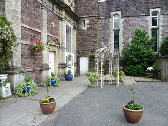 Hanging baskets and the floral white metal arch outside the Craig y Nos Castle theatre / ceremony room